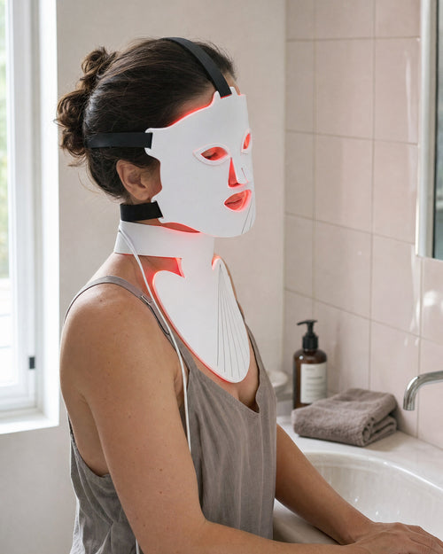 Holtrow Dawn worn — face shield and neck piece lit in red at a bathroom basin