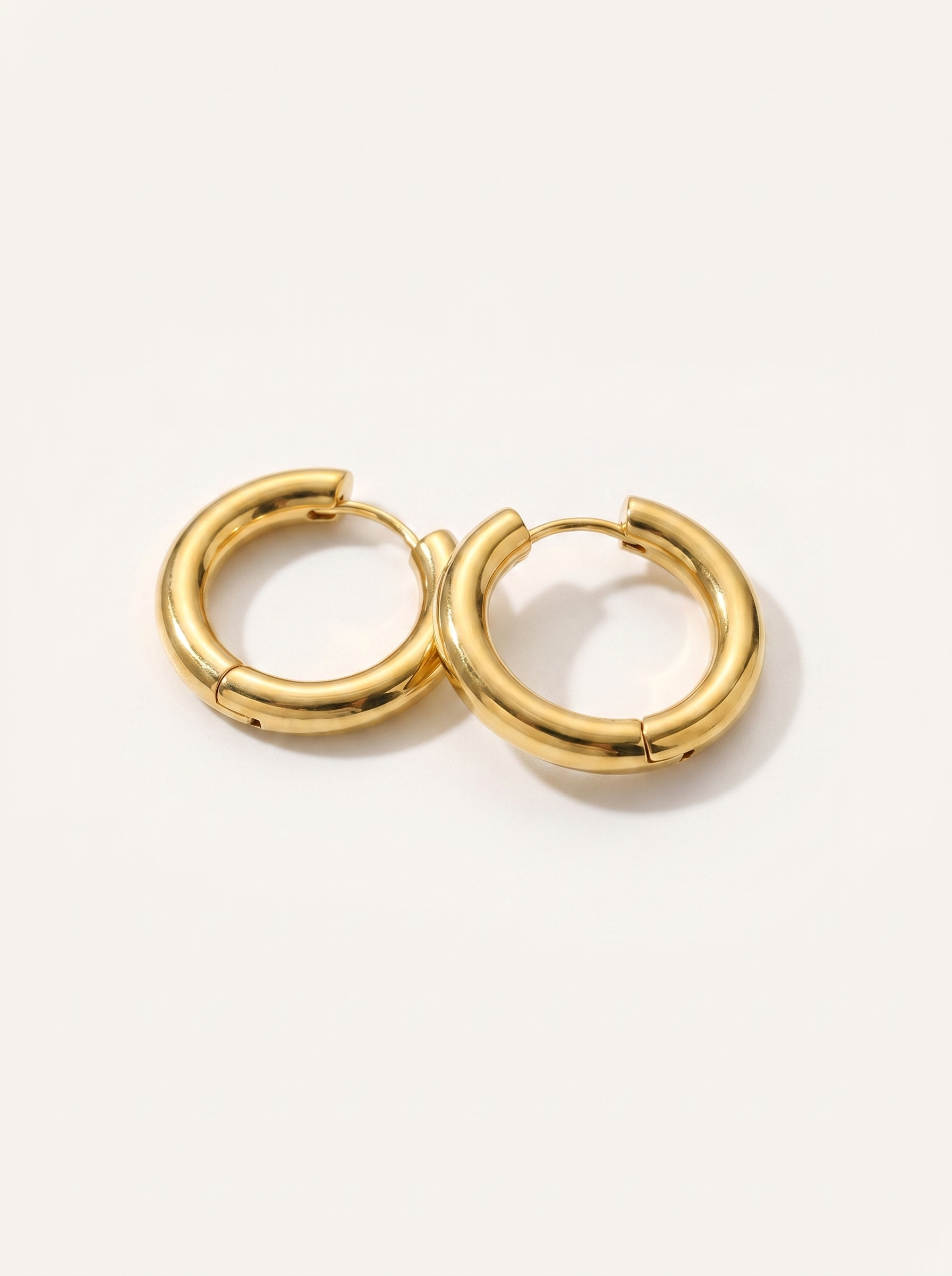 Cercle 18K gold huggie hoop earrings on clean white background