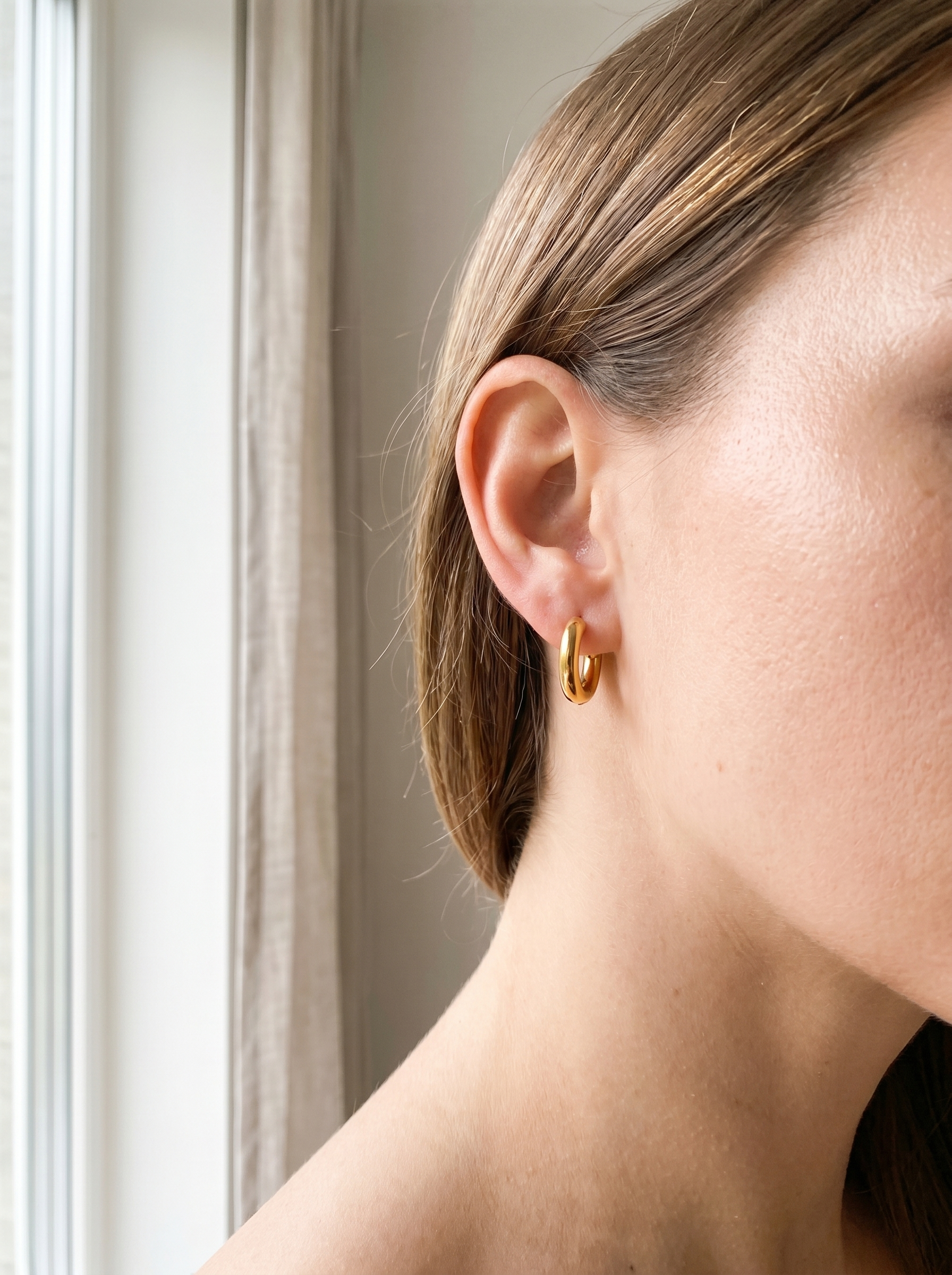 Cercle gold huggie hoop earring worn on the ear