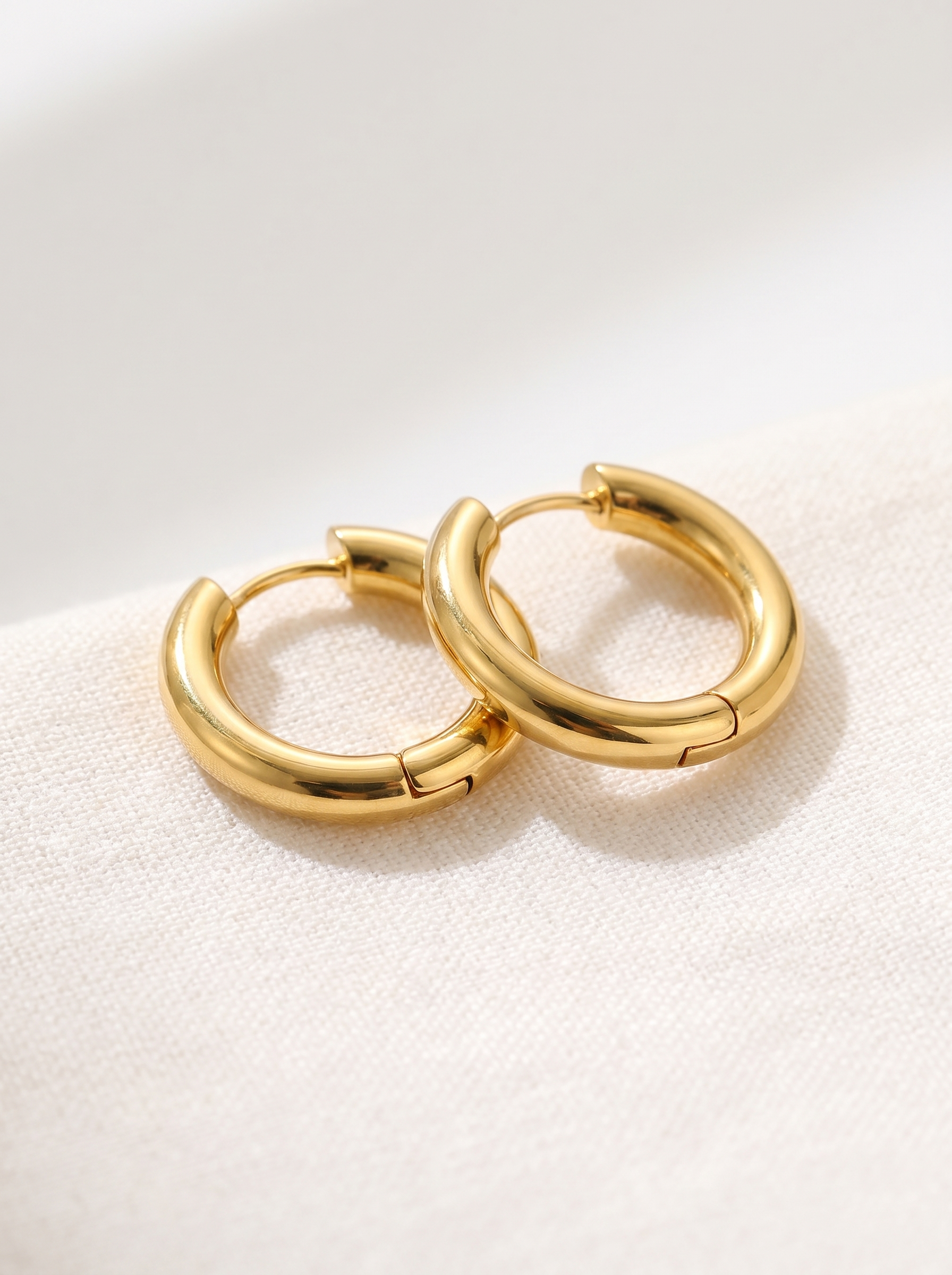 Cercle gold huggie hoop earrings macro detail on linen