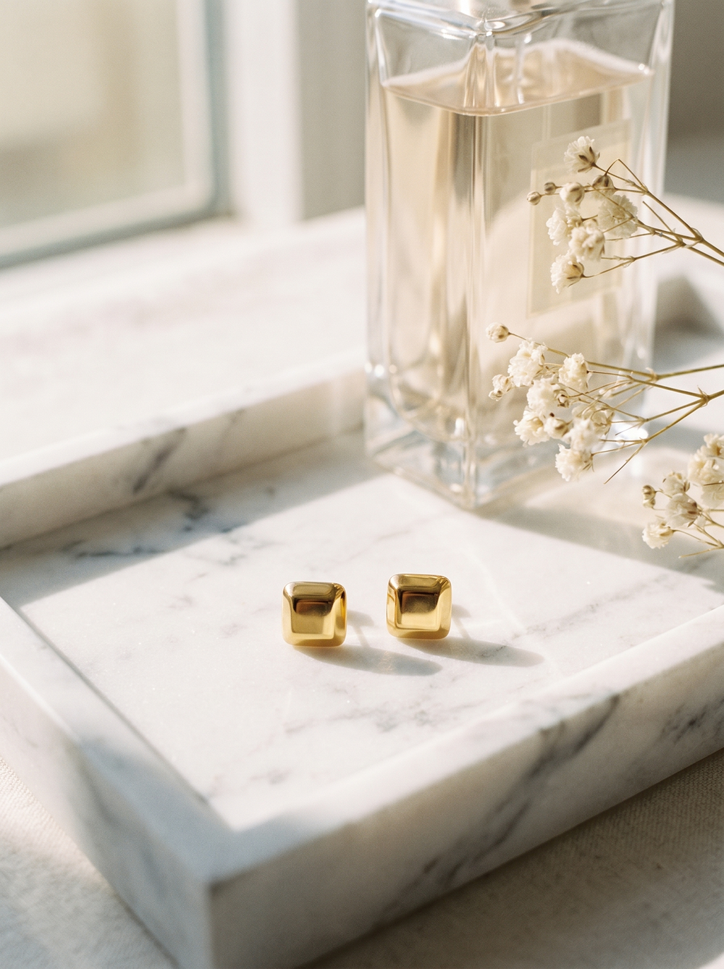Carre gold cube stud earrings on marble vanity tray