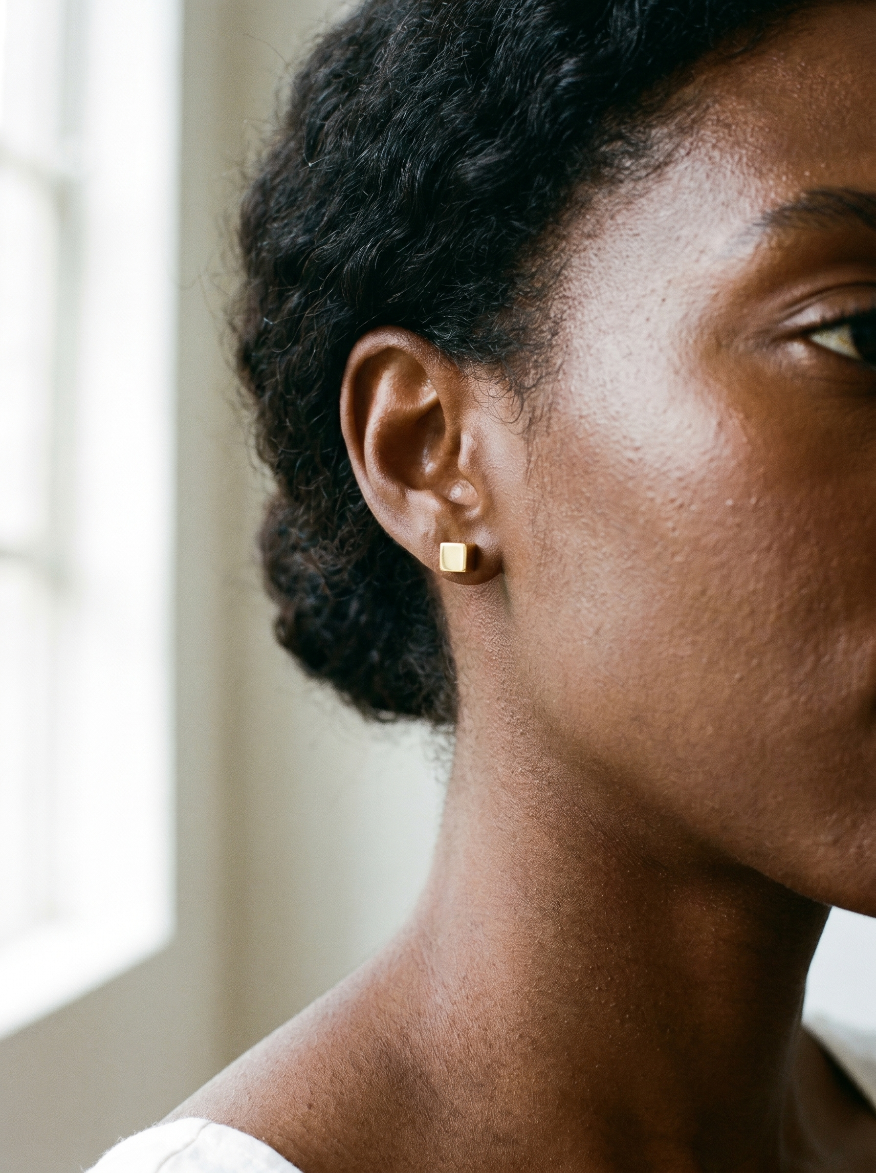 Carre gold cube stud earring worn on the ear