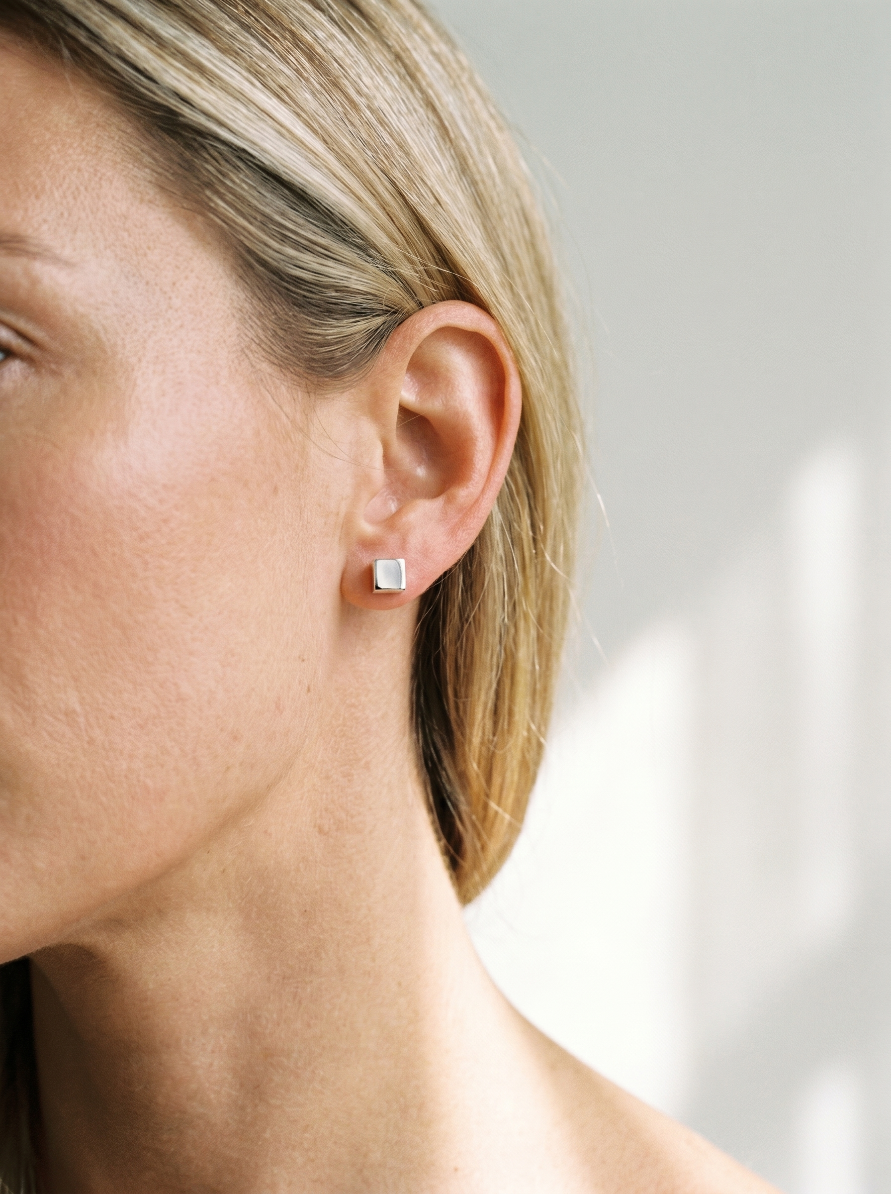 Carre silver cube stud earring worn on the ear