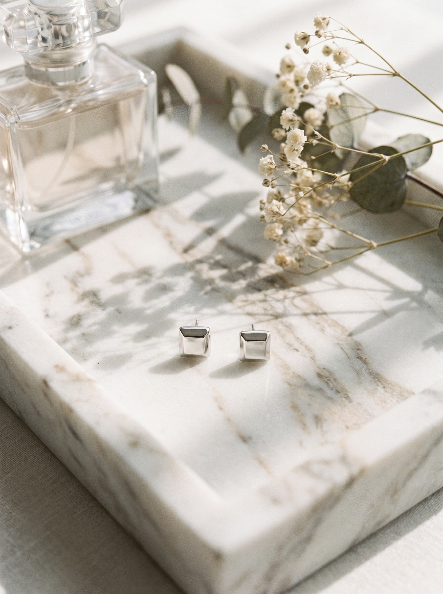 Carre silver cube stud earrings on marble vanity tray