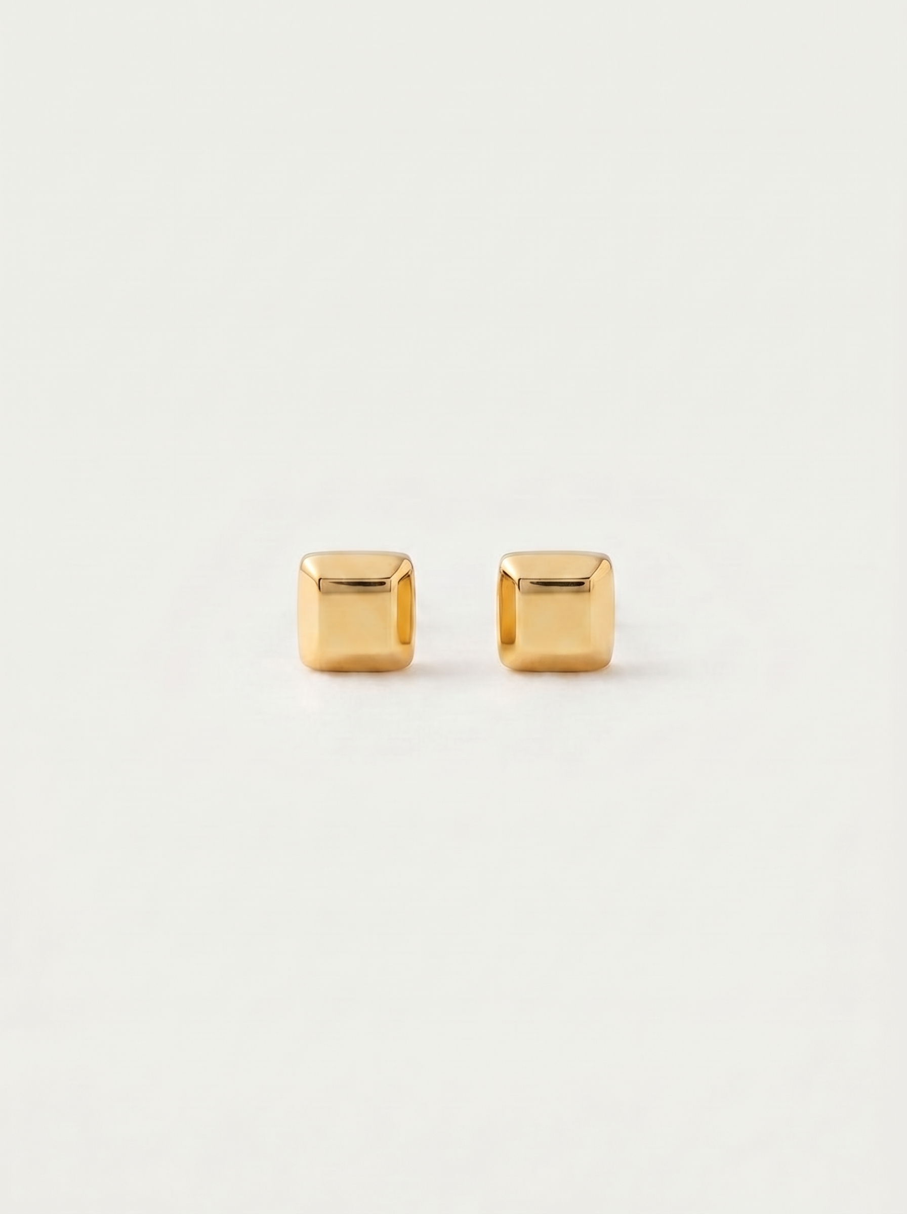 Carre chunky square gold cube stud earrings on warm off-white background