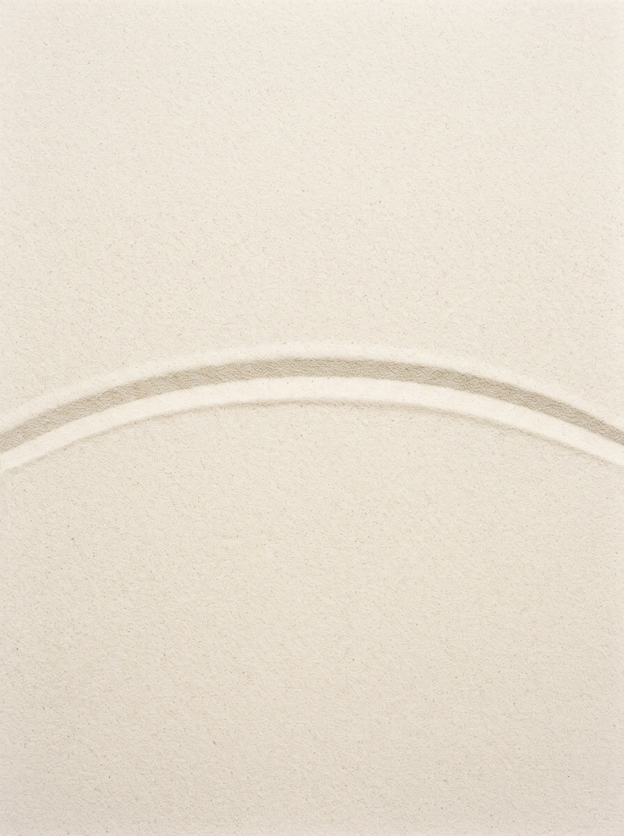 A single shallow arc raked through fine pale sand